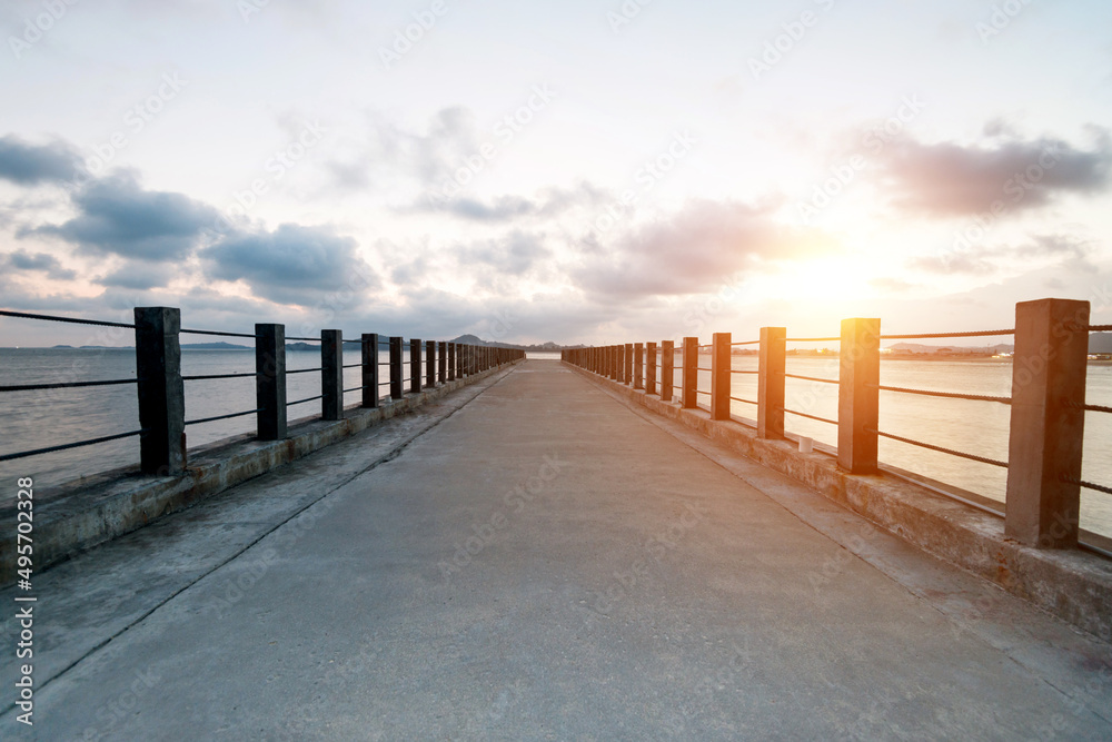 Obraz premium Concrete path to the sea at sunset.