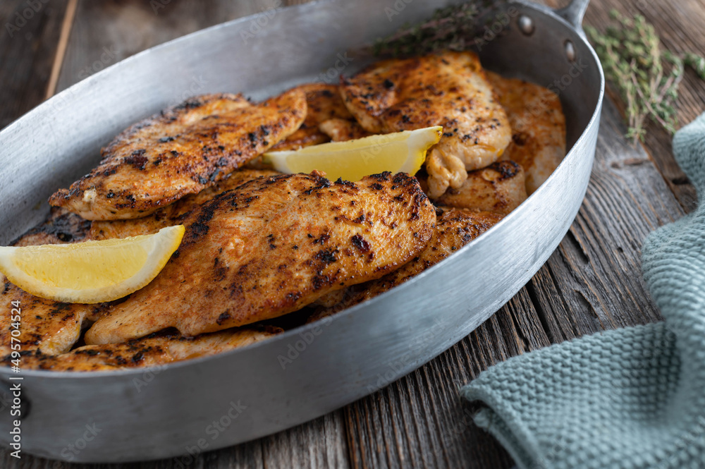 Pan fried chicken breast in a roasting pan on wooden table Pan fried chicken breast in a roasting pan on wooden table