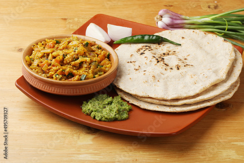 indian village food roasted egg plant and bhakri or Indian flat bread  Jowar Roti served with green chilli chutney traditionally called as Theccha in Marathi and spring onion beside  photo