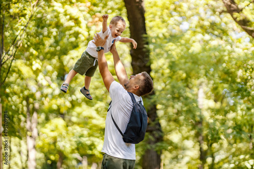 Father lifting his boy in the air and playing game with him in the forest.