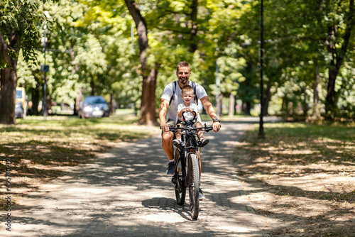 Father and son riding a bicycle in a park on sunny day and living healthy life. © dusanpetkovic1