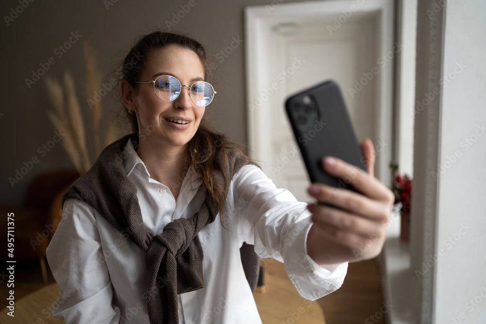 A woman with glasses in the office uses a phone video call with a colleague A woman with glasses in the office uses a phone video call with a colleague