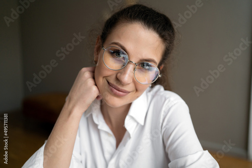 Portrait of a woman with glasses looking at the camera in a white shirt sitting in the office
