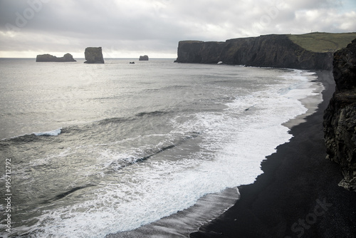 Scenic view of kirkjufjara beach and dyrholaey peninsula against cloudy sky in south Iceland photo