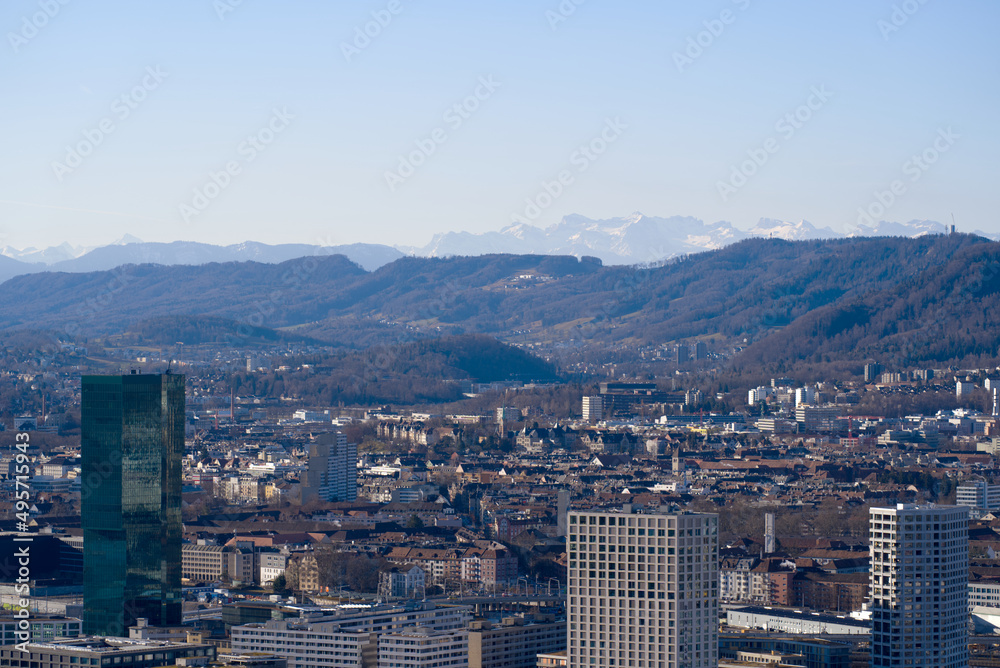 Aerial view over City of Zürich with Prime Tower skyscraper and industrial area and mountains in the background on a blue and cloudy spring morning. Photo taken March 14th, 2022, Zurich, Switzerland.