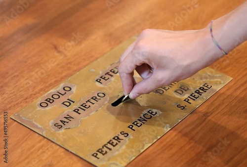 hand of the boy who puts a coin in the offering box for the offering of St. Peter s in the Vatican city photo