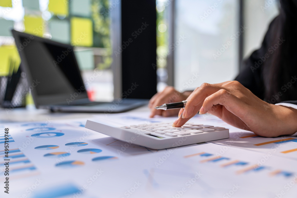 The hand of Asian woman is pressing calculator and prepare information for report to correct. While still holding a silver pen in finger. The hand of Asian woman is pressing calculator and prepare information for report to correct. While still holding a silver pen in finger.