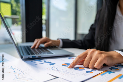 business woman using laptop analyzing graph document showing investment results and the operating results of the company