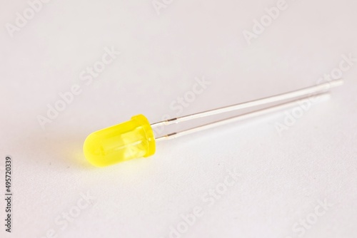 A top down studio portrait of a single yellow colored LED or color Light Emitting Diode lying on a white background, ready to be used in some kind of electronics PCB or circuit or print board.