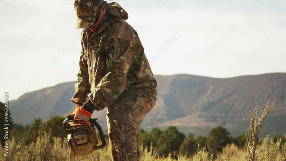 Medium shot of an outdoorsman using a chainsaw to cut up logs. Medium shot of an outdoorsman using a chainsaw to cut up logs.