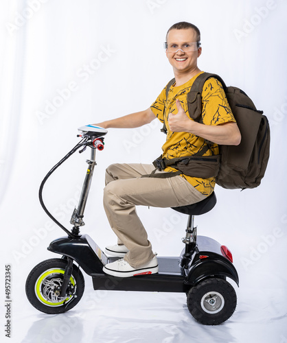 guy in an electric car. a man in the studio on a tricycle with a backpack. travel white background. electric scooter. ecological transport