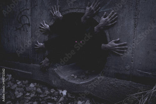 Creepy creature with multiple hands looking from the dark hole.