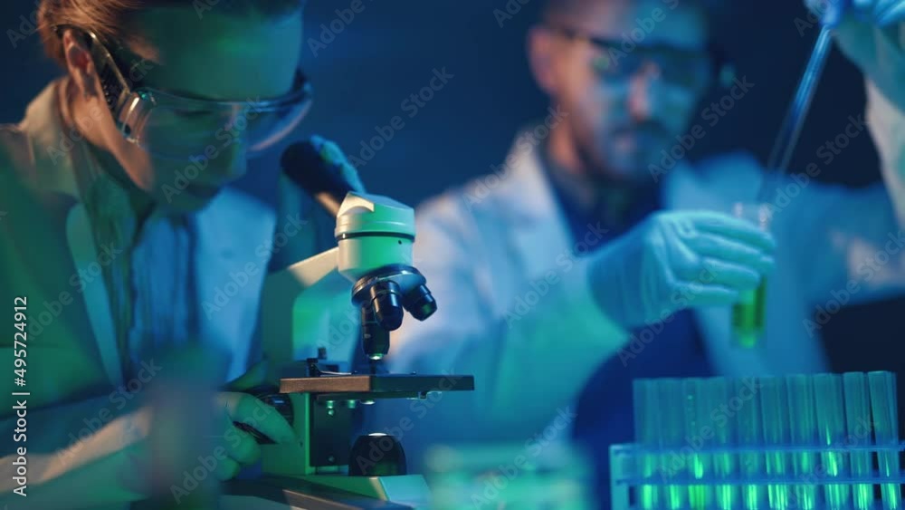 Scientists are analyzing samples in medical research laboratory. Scientific searching for vaccine with microscope to treat diseases in medicine. Pharmaceutical Lab and biotechnology development