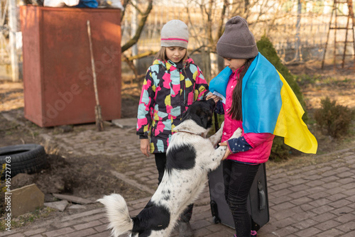 Ukraine military migration. two little girls with a suitcase. Flag of Ukraine, help. Crisis, military conflict