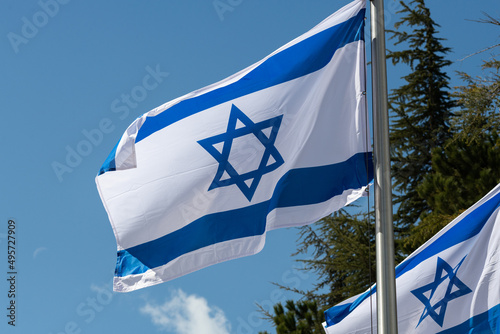 A blue and white, outstretched flag of the State of Israel on a pole in the Mt. Herzl military cemetery in Jerusalem. photo