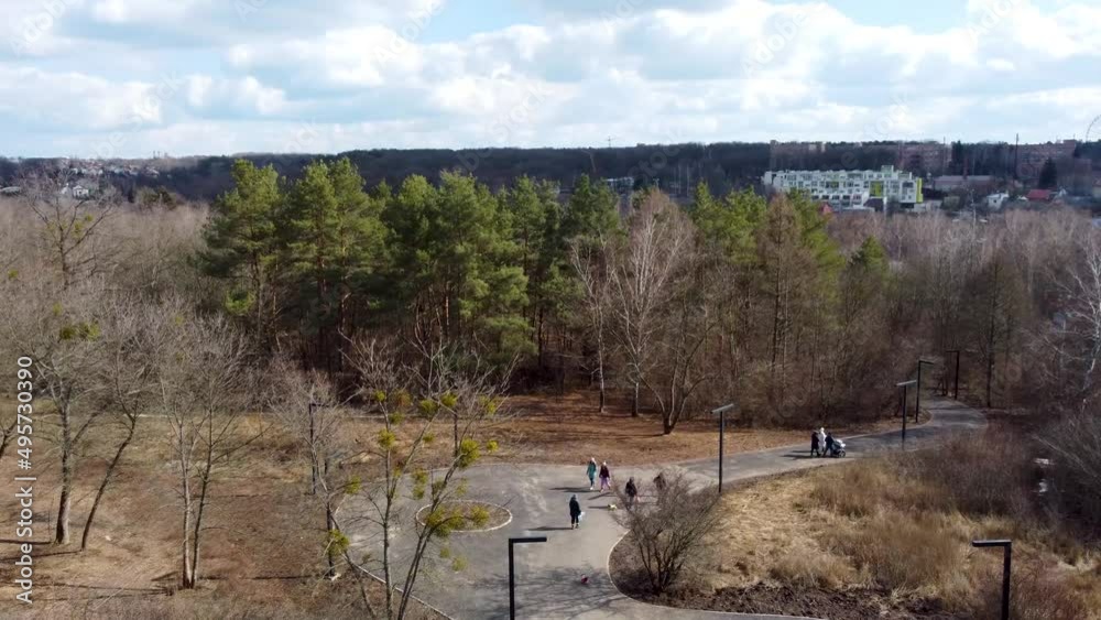 Aerial view on Sarzhyn Yar paths with walking people in early spring city park. High in trees in Kharkiv recreation area, Ukraine on sunny day