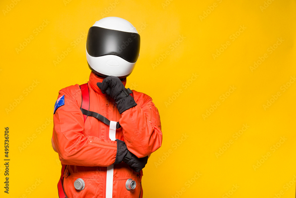 Astronaut with orange spacesuit with thoughtful gesture on yellow background