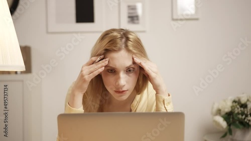 A blonde woman look at laptop screen work online think of problem solution. 