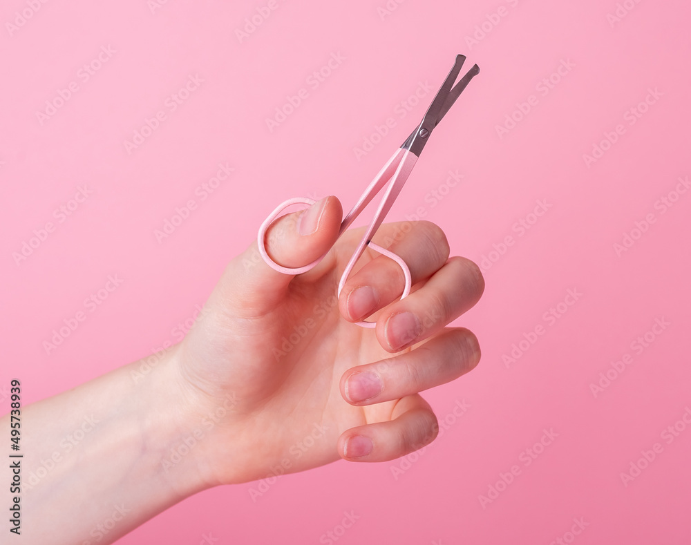 Woman hand holding nail scissors for manicure on pink background. Tool for beauty procedure. Hygiene and care concept. High quality photo Woman hand holding nail scissors for manicure on pink background. Tool for beauty procedure. Hygiene and care concept. High quality photo