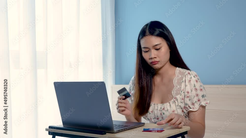 4K 50fps, Beautiful Asian girl, wearing a floral shirt, sitting in front of a laptop screen, is shopping online, picking up a credit card, looks stern, not happy,online shopping. 4K 50fps, Beautiful Asian girl, wearing a floral shirt, sitting in front of a laptop screen, is shopping online, picking up a credit card, looks stern, not happy,online shopping.