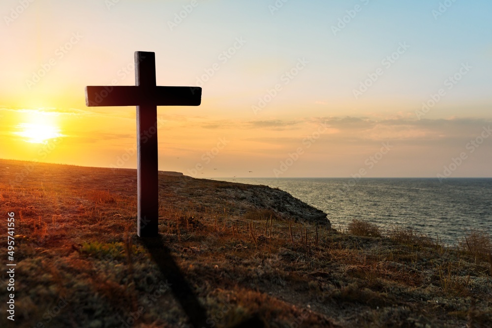 A christian cross at a scenic sunset or sunrise