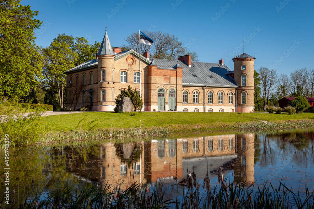 Old brick manor house in Lasila. Estonia, Baltic states. Landscape of the estate with reflection in the pond, spring sunny day. Today it is home to Lasila School.