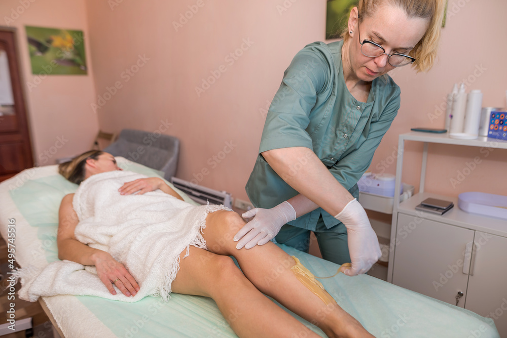 Fototapeta premium The process of epilation of the legs or parts of the female body using the sugaring method.