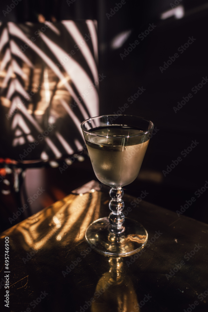 chilled white wine cocktail on brass gold table with palm tree background, glittering in the sunlight