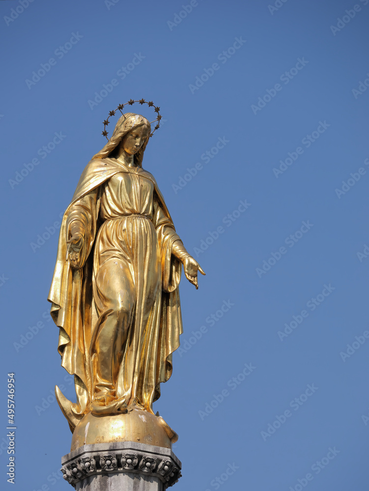 Vertical picture of a Holy Mary statue placed on top of a column in front of Zagreb Cathedral, Croatia