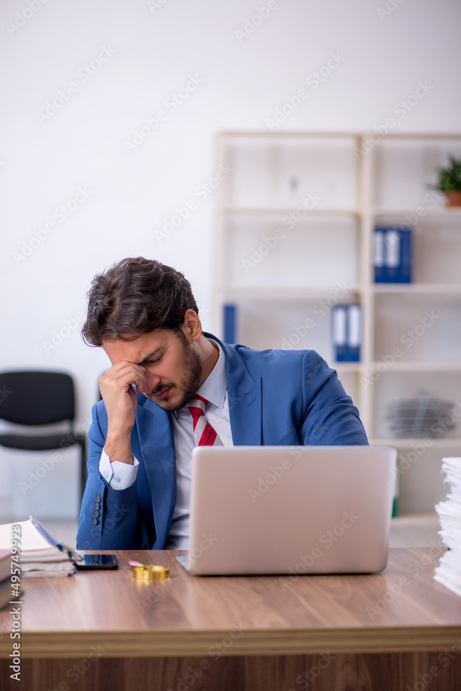 Young male employee and too much work in the office Young male employee and too much work in the office