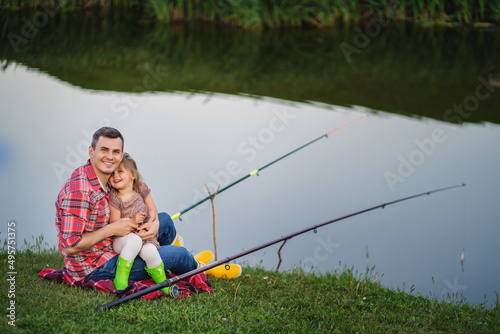 Happy Father and toddler girl together fishing in summer day on the lake.
