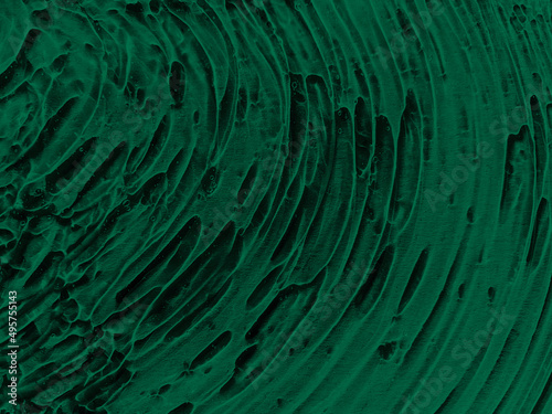 Transparent serum gel texture on dark green background in the sunlight. Skin care organic product bubble texture. Liquid facial cleanser smudged pattern.
