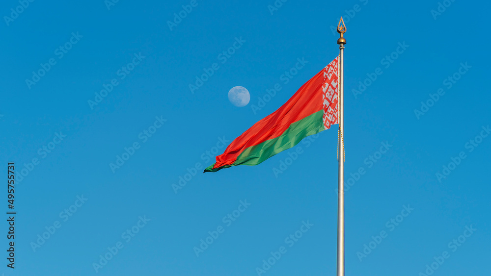 State flags of the Republic of Belarus are waving in the wind on blue sky with full moon background. Space for text. State flags of the Republic of Belarus are waving in the wind on blue sky with full moon background. Space for text.