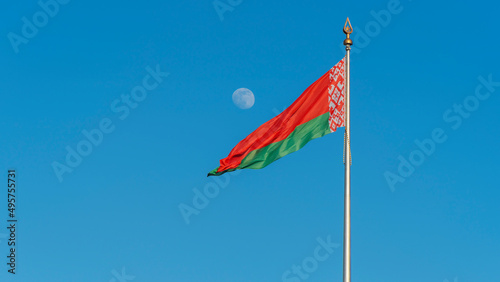 State flags of the Republic of Belarus are waving in the wind on blue sky with full moon background. Space for text.