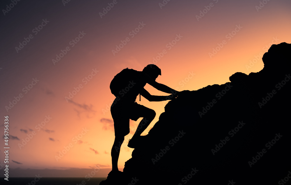 Man climbing up rocky mountain cliff 