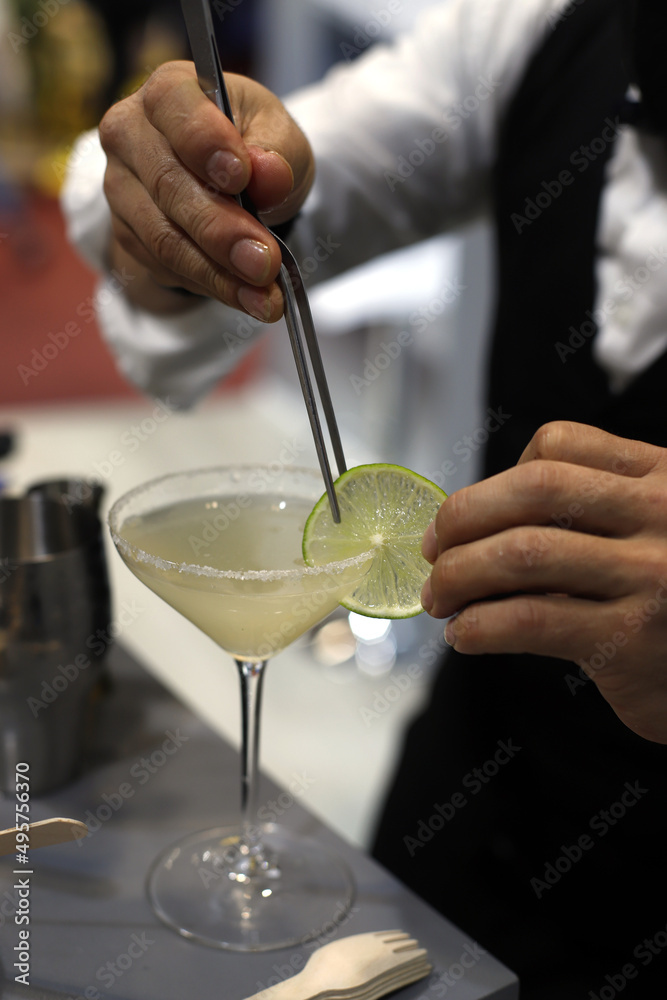 barman dando el toque final al coctel, con una rodaja de lima barman dando el toque final al coctel, con una rodaja de lima