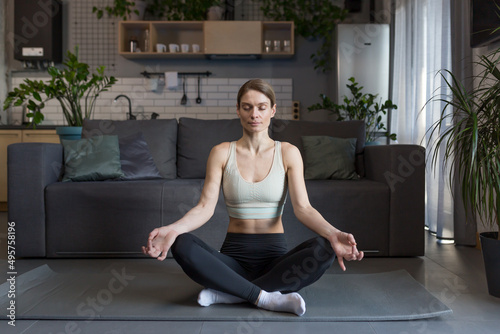 Woman at home sitting on the floor in the lotus position, meditating
