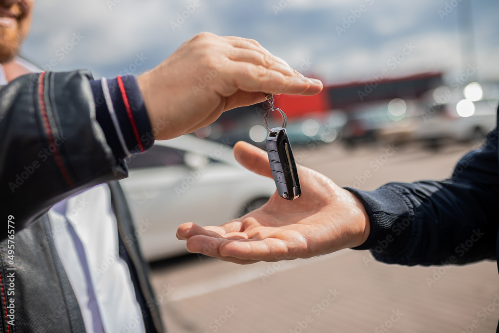 Fototapeta premium Сlose up. Hand giving a car key. Concept of successful car transaction sale-purchase deal