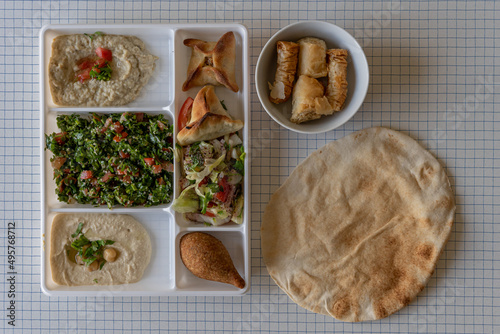 Paris, France - 03 17 2022: Top view of a plate of Lebanese specialties a pita bread and a bowl of pastries photo