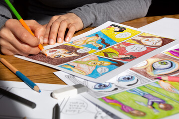 An artist draws comic book characters on paper with a pencil. Illustrated drawings of a multicolored storyboard.