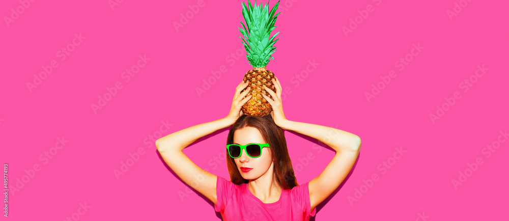 Fashion portrait of woman in sunglasses with pineapple on green background
