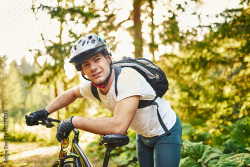 Tired bicyclist in sport clothes and helmet taking break after outdoors training. Healthy caucasian man spending free time for workout on fresh air. photo