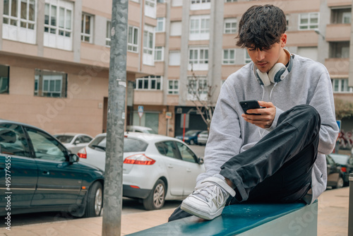 teen boy with mobile phone and headphones on the street