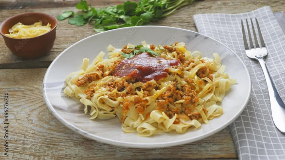 Pasta bolognese in a plate next to greens on a wooden table on a napkin Pasta bolognese in a plate next to greens on a wooden table on a napkin
