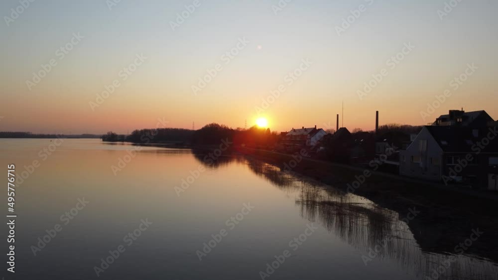 Silhouette of small coastal town and factory chimney near river Scheldt, aerial side fly view Silhouette of small coastal town and factory chimney near river Scheldt, aerial side fly view