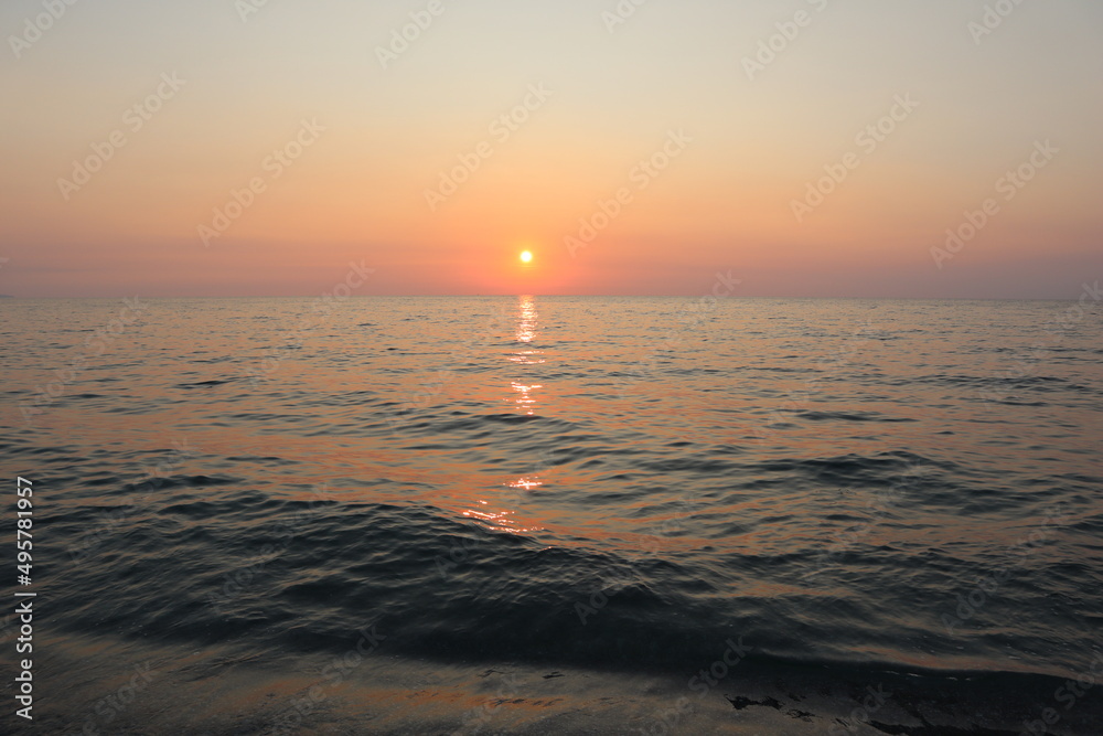 Fototapeta premium Sunset over the sea. Calm sea on a summer evening at sunset on the coast of Calabria, holidays at sea in Italy