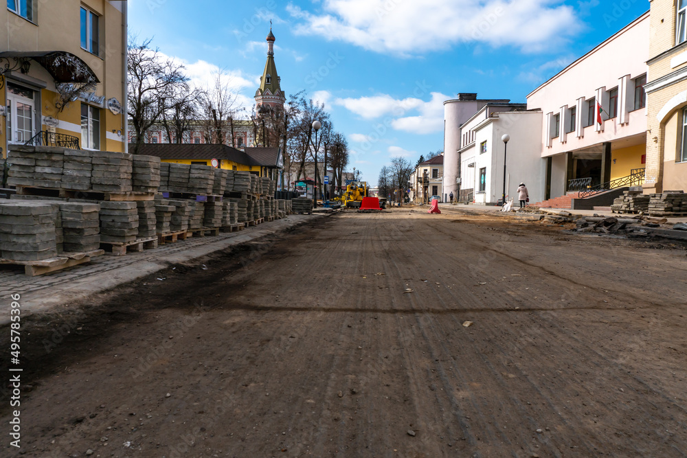 View of a wide city street where the sidewalk and asphalt are being repaired. Removal of old paving slabs for subsequent restoration of the roadway.
