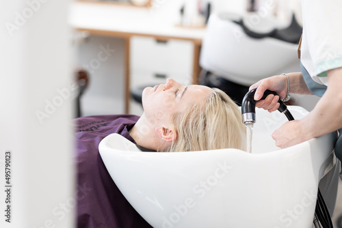 Professional hairdresser washing beautiful young woman's hair in the salon. Beauty procedure. Self care