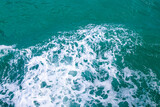 Emerald sea with white foam. Natural water surface background, top view.