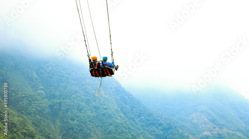 Two tourist are in a giant swing: famous tourist attraction swinging over a ravine in Ecuador
